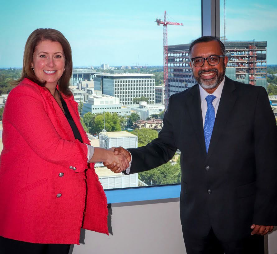 Reji Varghese shaking hands with Board President Kristina D. Lawson